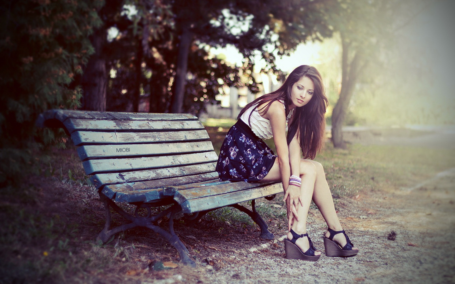 Девушка сидит на скамейке в парке